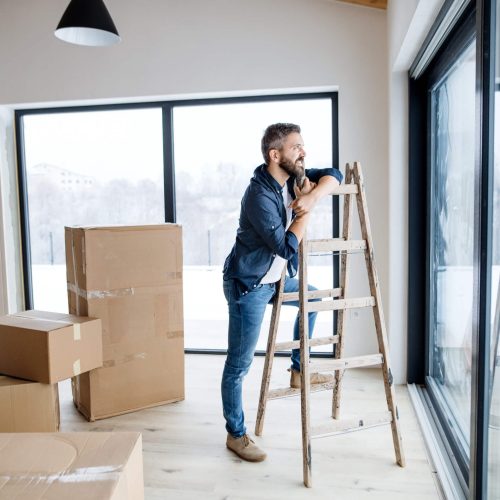 Man with cardboard boxes standing by a window